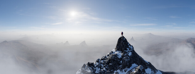 Lone Hiker On Snowy Mountain Peak Over Misty Valleys Under a Wide Blue Sky © edb3_16