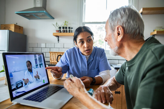 Nurse assisting senior with telehealth doctor visit at home