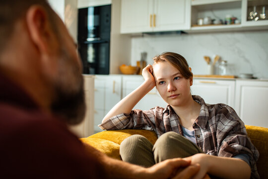 Parent and teen talking seriously in home kitchen