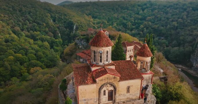 Cinematic drone shot of Motsameta Monastery with a smooth rotating pull-away movement. Revealing the medieval Orthodox complex and deep river gorge near Kutaisi, Georgia.