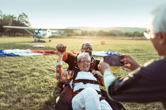 Happy senior woman celebrating tandem skydive landing at airfield
