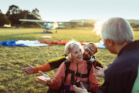 Happy senior with instructor after tandem skydive at airfield