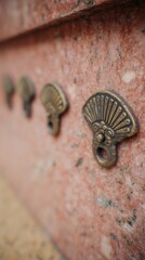 Decorative metal fan-shaped adornments on a granite surface. Ornate brass elements arranged on a textured stone, with an artistic aesthetic.