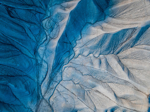 Aerial view of nature's stunning canvas of contrasting blues and beige, etched with intricate patterns resembling branching rivers and veins, Hanksville, Utah, United States.