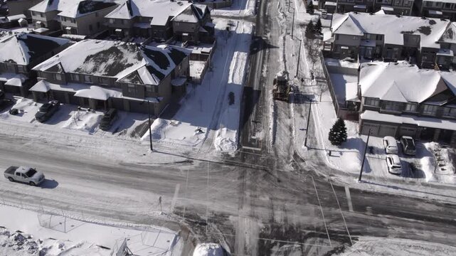 Snow land leveller grader clearing suburban street - from above