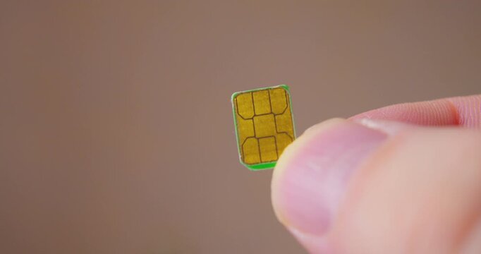 Detailed close-up of fingers grasping a SIM card compatible with smartphone.