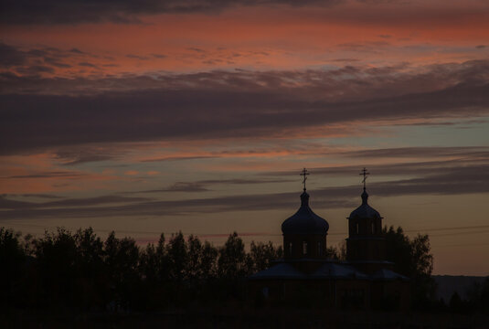 Bright blue-red sunset sky on summer evening, and dark silhouette of two domes of Orthodox church