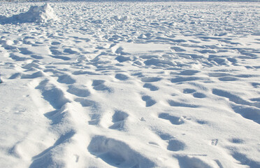 Obraz premium Deep tracks in white snow in winter, light and shadows on surface in sunlight