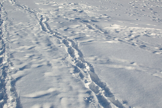Deep tracks in white snow in winter, light and shadows on surface in sunlight