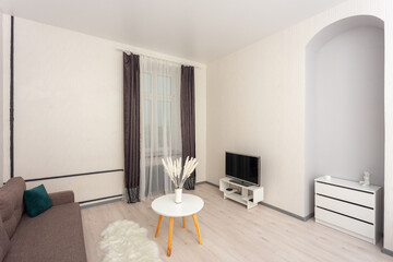 Bright minimalist living room with sofa, TV stand, round coffee table