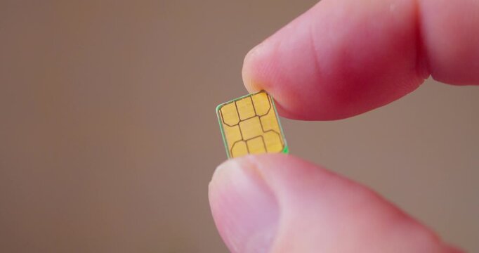 Macro shot of fingers gripping a contemporary SIM card used in smartphone.