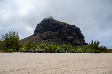 Dramatic view of Le Morne Brabant mountain from a sandy beach under a cloudy sky in Mauritius