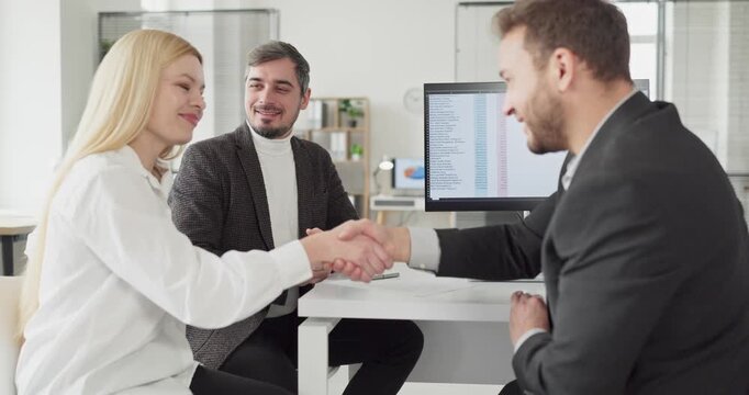 Clients couple meet advisor, handshake confirms contract. Banker outlines terms during consultation, guiding agreement process in an office meeting. Concept of partnership and deal closure.