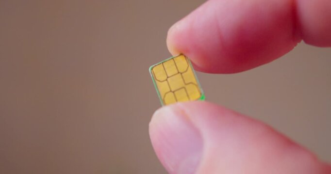 Detailed close-up of fingers grasping a SIM card compatible with smartphone.