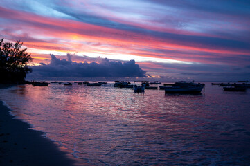 Dramatic purple sunset over the ocean with silhouetted fishing boats in Tamarin Bay, Mauritius