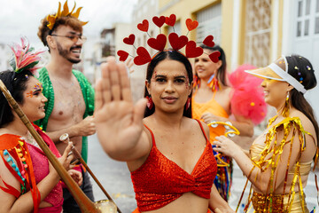 Woman raising her hand in a stop gesture to reject harassment during a Brazilian carnival street...