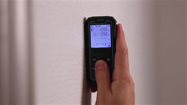 Un agent immobilier utilisant un t&eacute;l&eacute;m&egrave;tre laser pour mesurer la surface d'un bien immobilier.