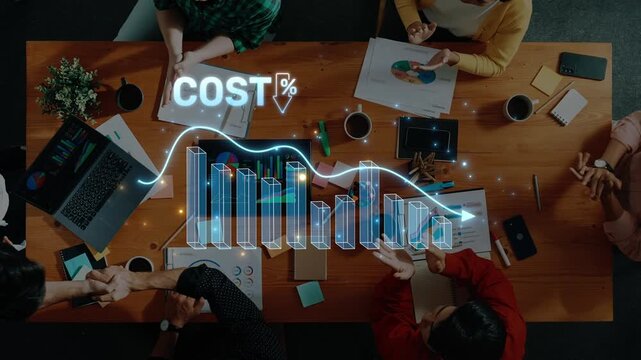 A high-angle view of a business meeting where a team engages in cost analysis, showcasing graphical data visuals and collaborative decision-making around a wooden table. Raster