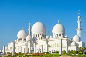 Fototapeta premium Sheikh Zayed Grand Mosque with multiple domes and minarets under clear blue sky in Abu Dhabi, United Arab Emirates. Islamic architectural heritage. Travel and tourism in UAE