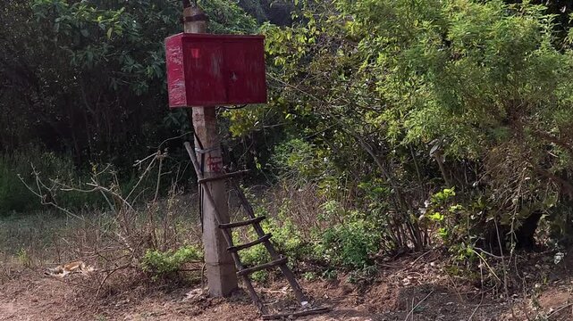 An irrigation box sits on a pole, accessed by a rustic wooden ladder. This setup highlights the simple, manual solutions used in rural farming to manage water flow & sustain crops in rugged landscape.