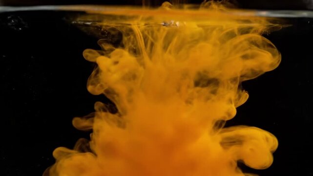 Yellow powder dissolving in water creates swirling patterns. Vibrant yellow powder mixes with water, forming colorful designs and clouds.