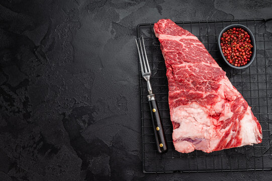 Fresh raw beef shoulder chuck cut with rich marbling on black textured background. BBQ steak meat with seasoning and copy space.