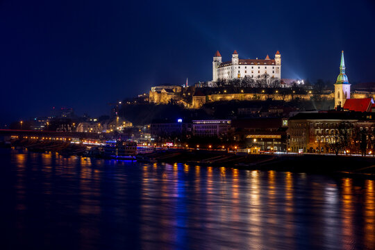 illuminated white Bratislava Castle above the Danube, against the background of a dark evening sky