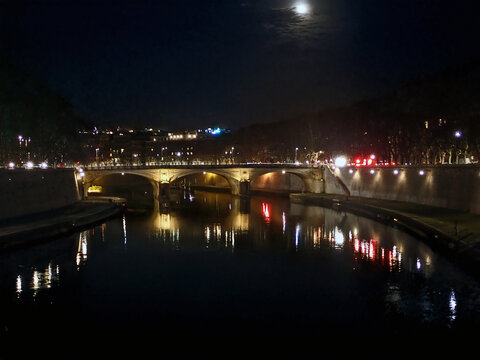 Veduta notturna del fiume Tevere con riflessi di luci sul ponte e la luna nel cielo nuvoloso, Roma, Italia 217