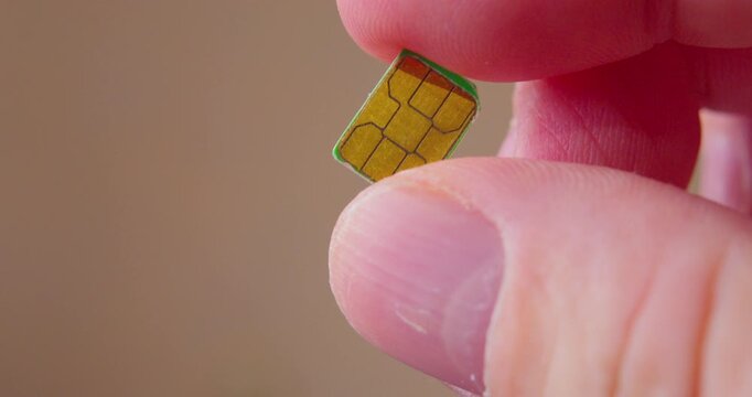 Modern technologies. Close-up video of fingers holding a SIM card designed for smartphone.