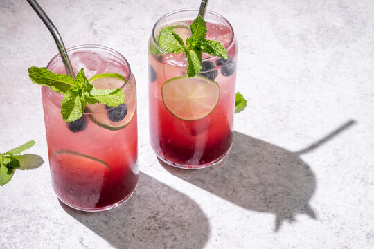 Fresh berry drinks with mint on a simple background