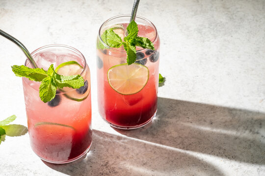 Fresh berry drinks with mint on a simple background