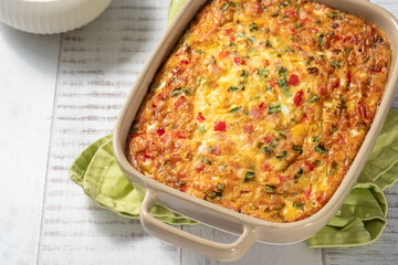 Baked egg dish with vegetables served on a wooden table with a side of greens