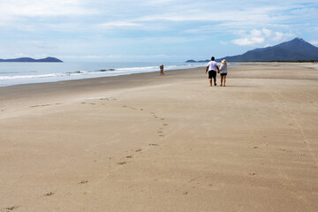 Unrecognized people walking on a seemingly deserted beach.
