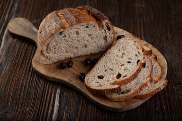 Rustic Olive Bread Presentation on Wood Background. Sliced Olive Bread on Dark Wooden Table. Artisan Olive Bread Slices on Rustic Background.