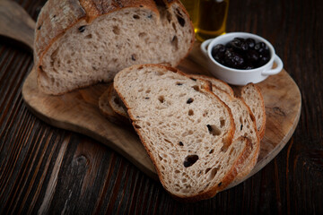 Rustic Olive Bread Presentation on Wood Background. Sliced Olive Bread on Dark Wooden Table. Artisan Olive Bread Slices on Rustic Background.