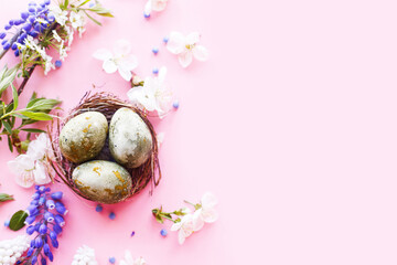 Easter flat lay. Stylish easter eggs in nest and cherry flowers on pink background. Easter celebration, season greetings mockup. Spring modern floral banner © sonyachny