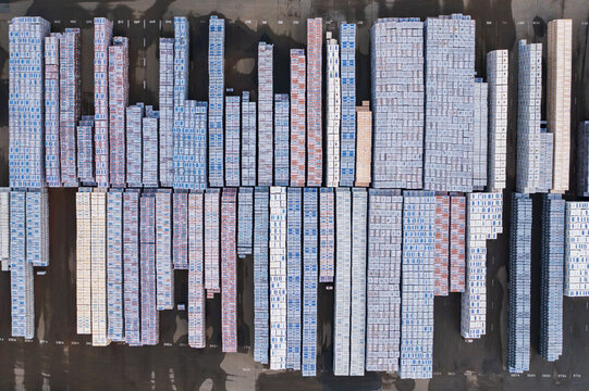 Aerial view of neatly stacked building materials casting subtle shadows on the asphalt, creating a geometric pattern of textures and tones, Gendt, Gelderland, Netherlands.