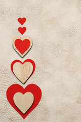 Valentine&rsquo;s Day background with red and wooden hearts on beige textured surface. Copy space