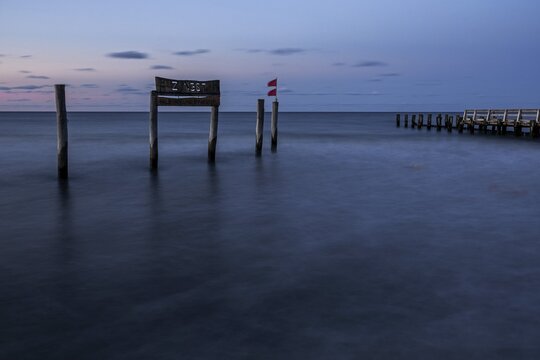 Wooden sign in the sea with inscription Zingst and wooden walkway, long exposure, evening light, Zingst, Fischland-Dar&szlig;-Zingst, Western Pomerania National Park, Mecklenburg-Western Pomerania, Germany