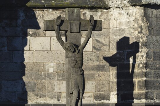 Stone cross with shadow cast, cathedral cemetery near Cologne Cathedral, Cologne, North Rhine-Westphalia, Germany