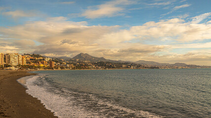 Sunny Malaga Beachfront Cityscape With Palm Trees, Ocean, and Mountain Backdrop at Dusk