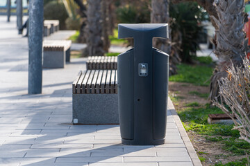 Dog waste bin dispenser in city park on sunny sidewalk