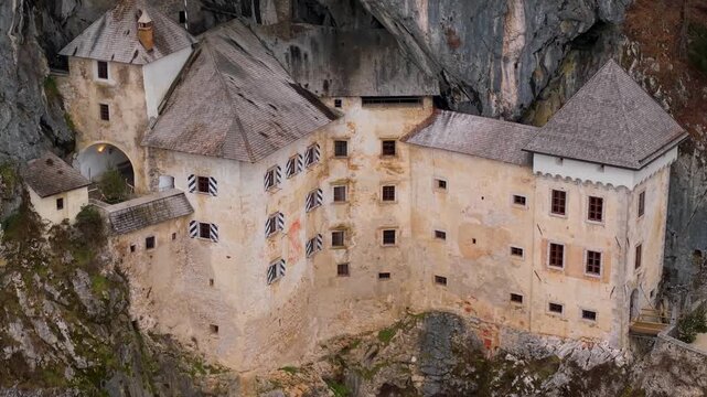 Cinematic Aerial View of Predjama Castle in Slovenia. Medieval Fortress Built into a Cave Mouth, Close-up and Pull-away Drone Shot of Gothic Castle Architecture and High Cliffs, 4K Footage