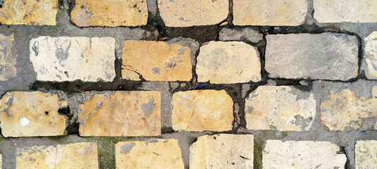 Fototapeta premium Vista superior de un pavimento de adoquines de piedra antigua con texturas desgastadas y juntas de cemento gris