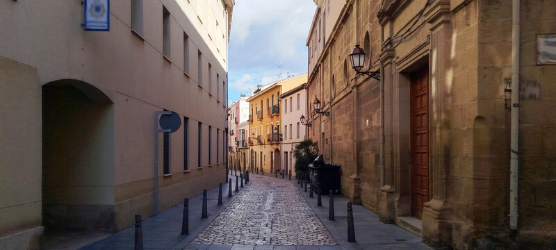 Calle estrecha empedrada en un casco antiguo con fachadas de edificios hist&oacute;ricos bajo un cielo azul con nubes de Logro&ntilde;o, Espa&ntilde;a