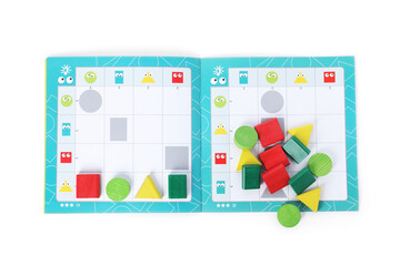 Open book and colorful pieces of geometrical sudoku for children isolated on white, top view