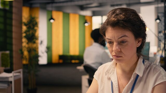 Frowning businesswoman with confused and skeptical expression at desk, appearing uncertain and indecisive reviewing visual data on laptop. Undetermined irregular performance metrics, confusion.