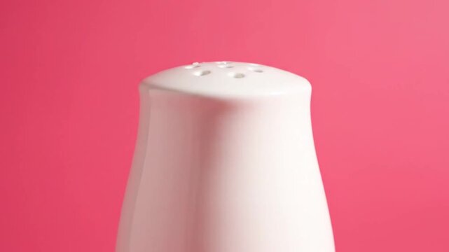 White Salt Shaker on Pink Background with Hard Light and Shadow.