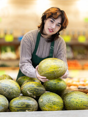 Fototapeta premium Woman employees in uniform holding fresh pumpkin in grocery shop