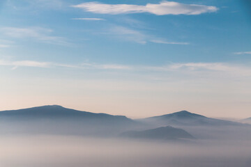 Misty mountain landscape with soft morning light and fog layers